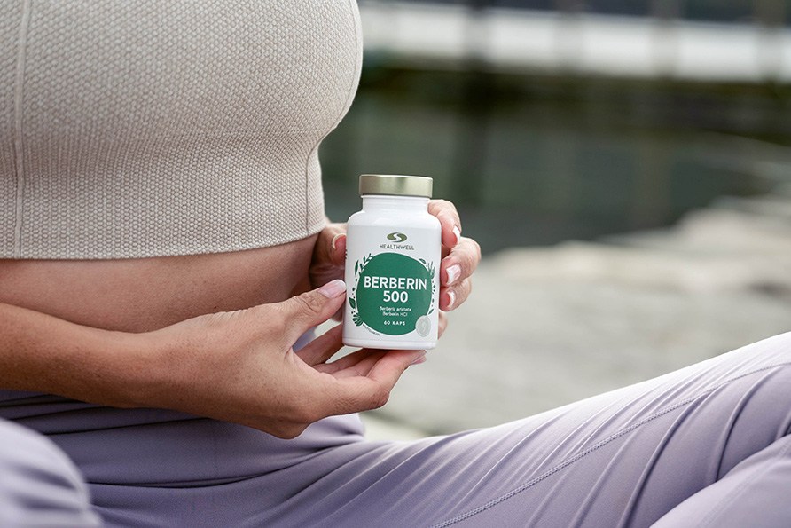 Kvinde holder en Healthwell Berberin 500 udendørs ved vandet.