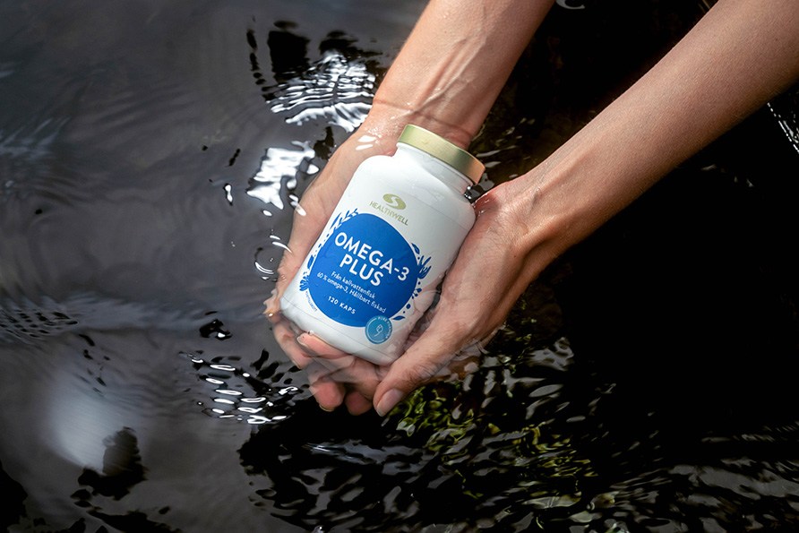 Et par h�nder holder en b�tte Healthwell Omega-3 Plus i vandet. 