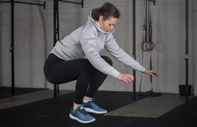 En kvinde hopper op på en høj kasse, i et træningscenter. En kvinde hopper op på en høj kasse, i et træningscenter.