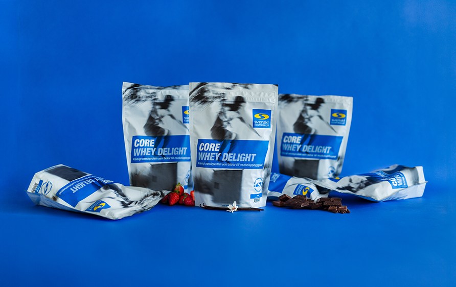 Flere forskellige varianter af Core Whey Delight str ved siden af hinanden, med en bl baggrund.