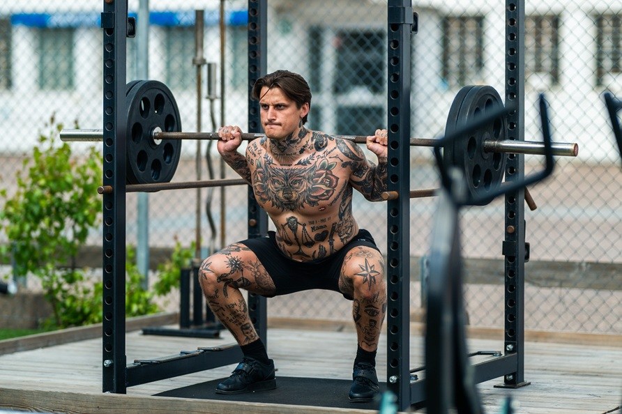 Mand trner udendrs og laver squatvelse.