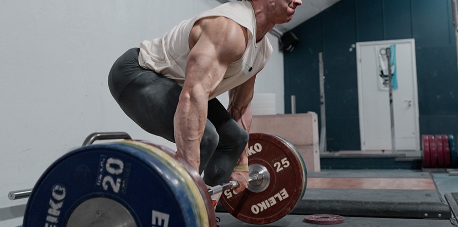 Mand der sidder på hug for at løfte en skivstang. Mand der sidder på hug for at løfte en skivstang.