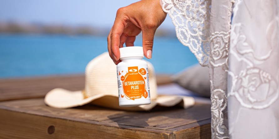 En kvinde holder en b�tte Healthwell Betacaroten Plus, udend�rs.
