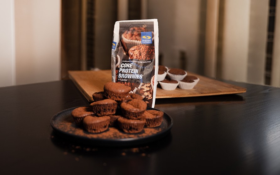 F�rdiglavet proteinbrownies p� et fad med en pose Core Protein Brownies bagemix i baggrunden.