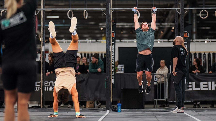 Billede af to m�nd, der tr�ner CrossFit, en p� h�nderne og en h�ngende i ringe.