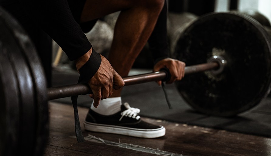 En person der bruger lftestroppe p en vgtstang, der er lastet med vgte under styrketrning.