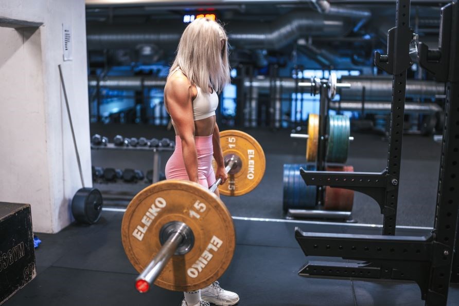 Kvinde holder shaker og sidder p� en b�nk i et fitnesscenter.