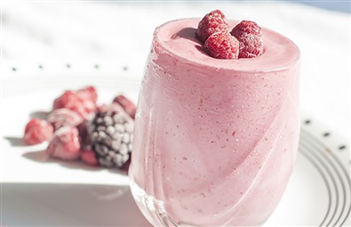 En jordb�r fitnesshake i et glas med hindb�r p� toppen.