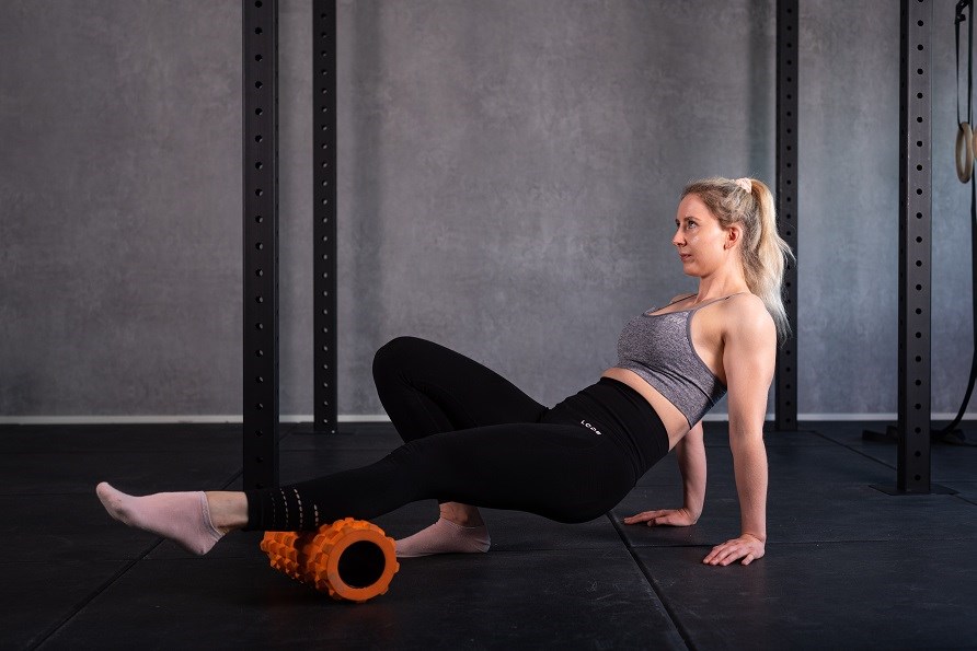 Trænende pige bruger en foam roller til kalvene.