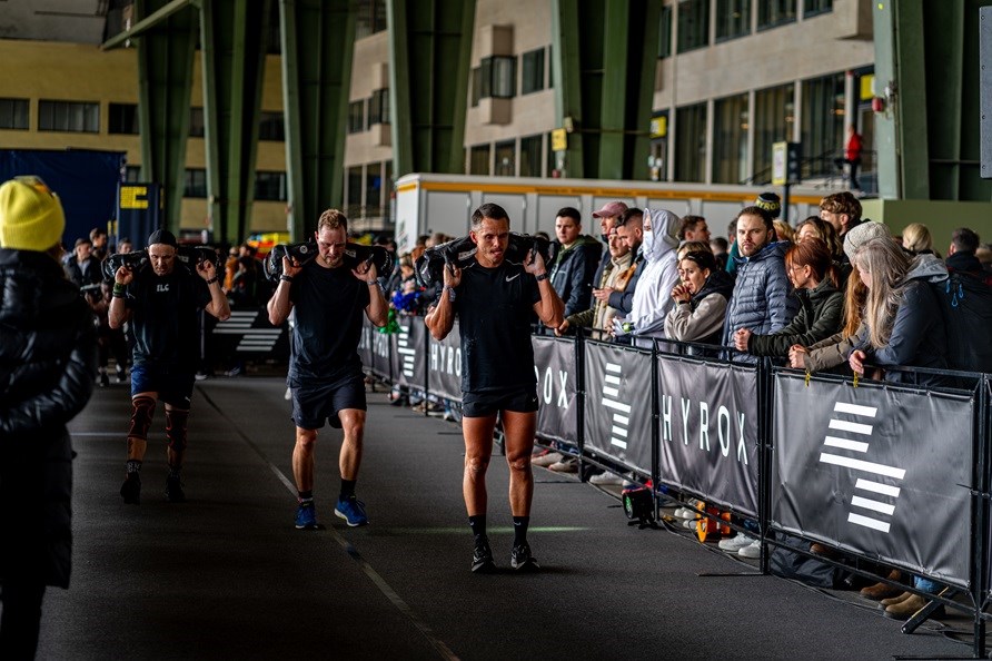 Hyrox-konkurrence hvor mnd gr lunges med sandsk.