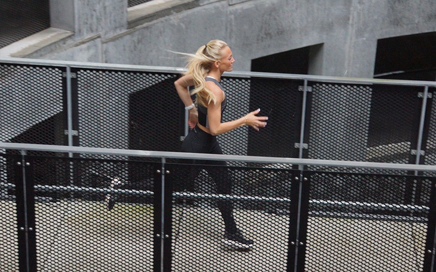 En kvinde lber udendrs p en metal bro.