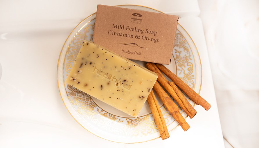 Mild Peeling Soap Cinnamon & Orange, dens emballage og kanelstnger i en hvid porcelnsskl med gyldent mnster.