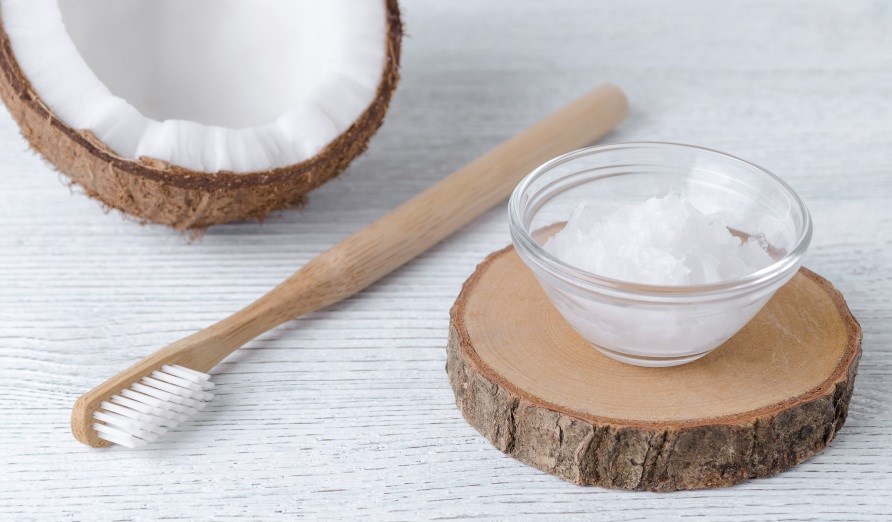 Kokosolie i en glasskål, en tandbørste sammen med en halv kokosnød. Kokosolie i en glasskål, en tandbørste sammen med en halv kokosnød.