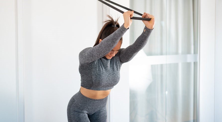 Kvinde laver øvelsen triceps push downs med elastik. Kvinde laver øvelsen triceps push downs med elastik.