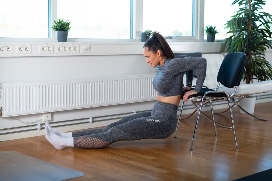 Kvinde der laver øvelsen dips på en stol. Kvinde der laver øvelsen dips på en stol.