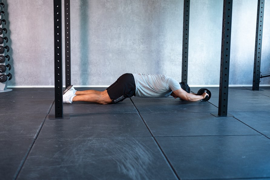 En mand er i udstrukket position med mavehjulet i hnderne.