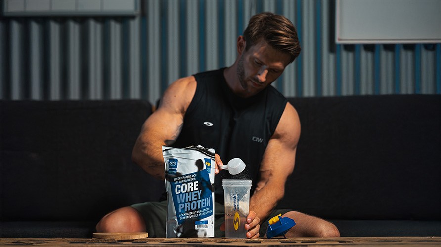 En mand sidder bag en pose Core Whey Protein og er ved at lave en proteinshake.