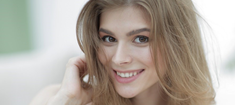 Et nrbillede af en kvinde der smiler til kameraet.