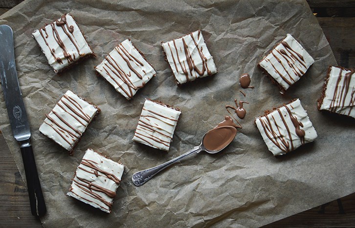 Stykker af brownie-cheesecake ligger p en bradepande.