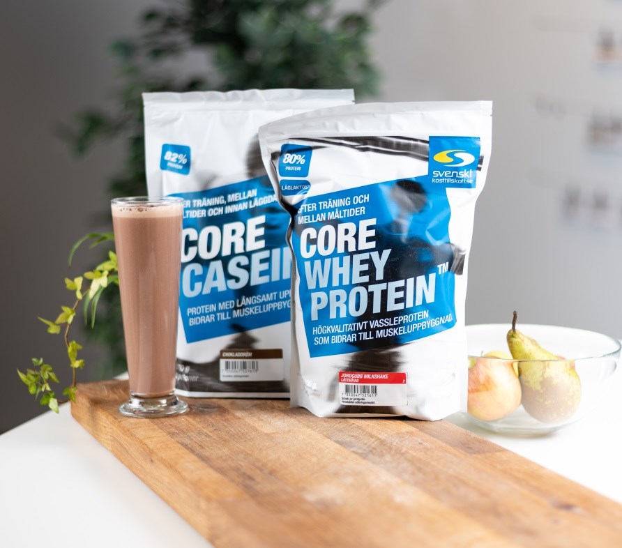 Core Whey Protein og Core Casein str p et bord sammen med en proteinshake med chokoladesmag.
