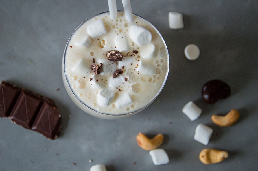 En sund version af en rocky road smoothie str p et bord med ndder, skumfiduser og chokolade ved siden af