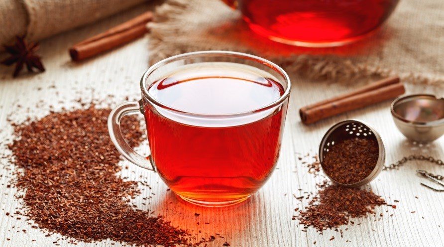 Et krus med rød te, omringet af løs rooibos te. Et krus med rød te, omringet af løs rooibos te.
