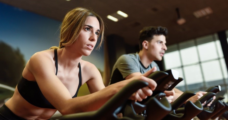 Kvinde og mand sidder p hver deres spinningcykel.