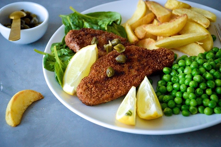 En tallerken med schnitzel, kartoffelbde og rter.