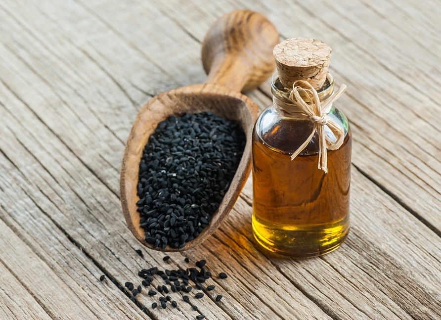 Sortkommenolie i et glas ved siden af en ske sortkommenfr�.