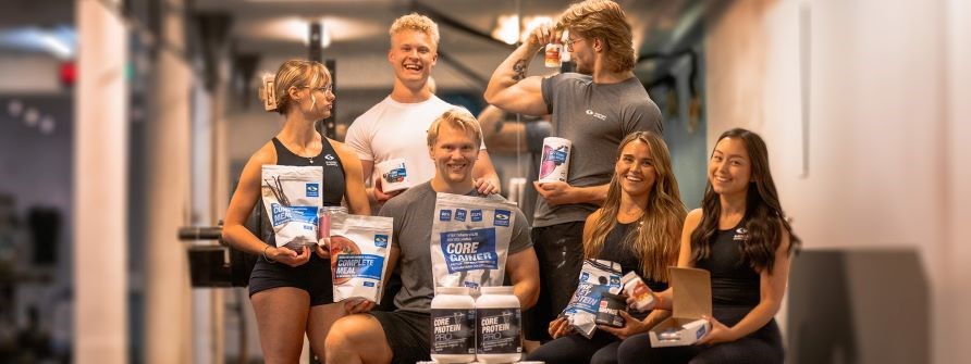 Seks unge kvinder og mnd str i et fitnesscenter med forskellige tilskud til trningen