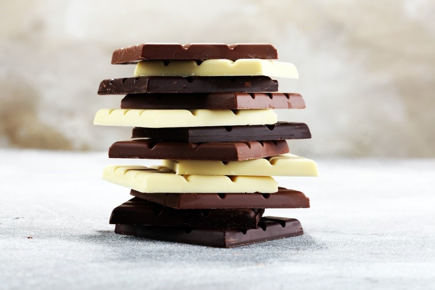 Hvide, mlke- og mrke chokoladebarer er stablet ovenp hinanden.