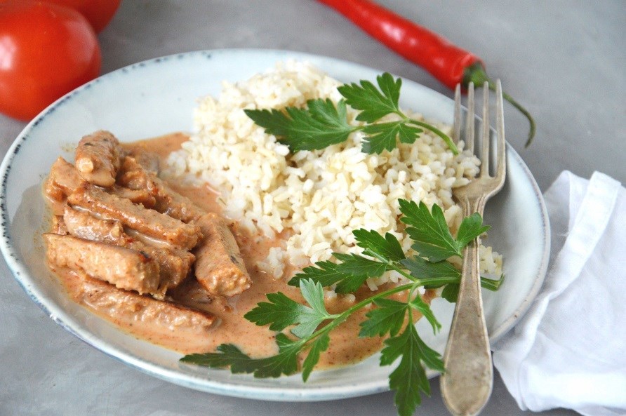 En tallerken med en portion stroganoff med kyllingeplser og ris.
