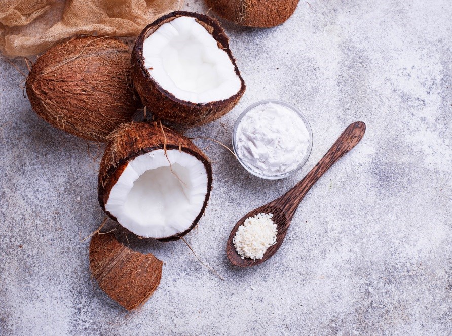 Kokosndder, en skl med kokosolie og kokosflager p en gr stenyderflade.