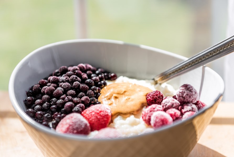 En skl med proteinrig havregryn toppet med forskellige frosne br og peanut butter.