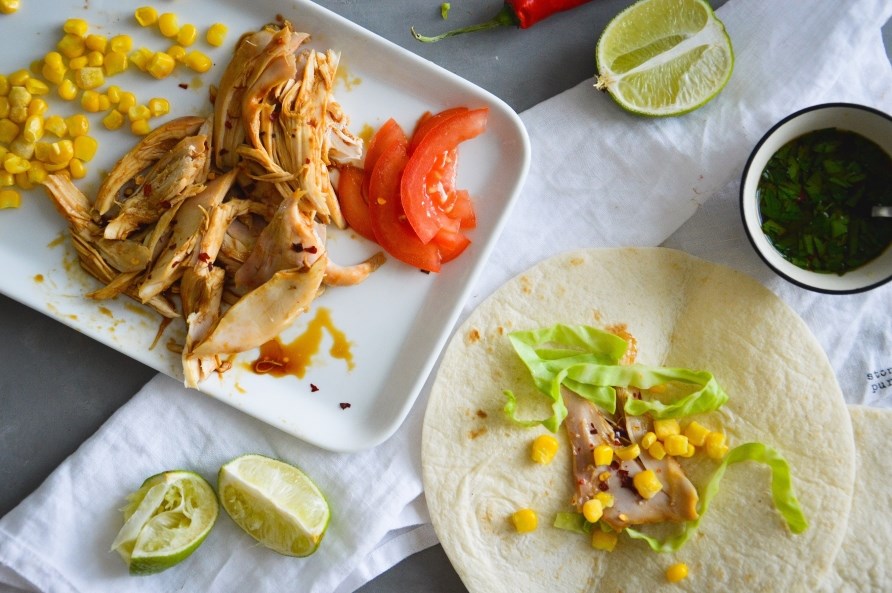 Pulled chicken ligger p en tallerken klar til at blive puttet i et tortillabrd.