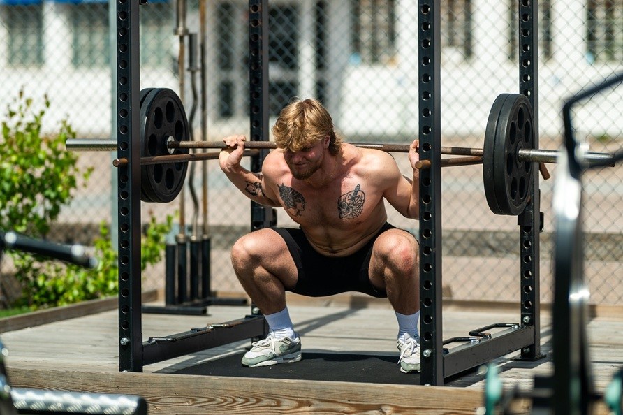 En mand udfrer trningsvelsen squat udendrs.
