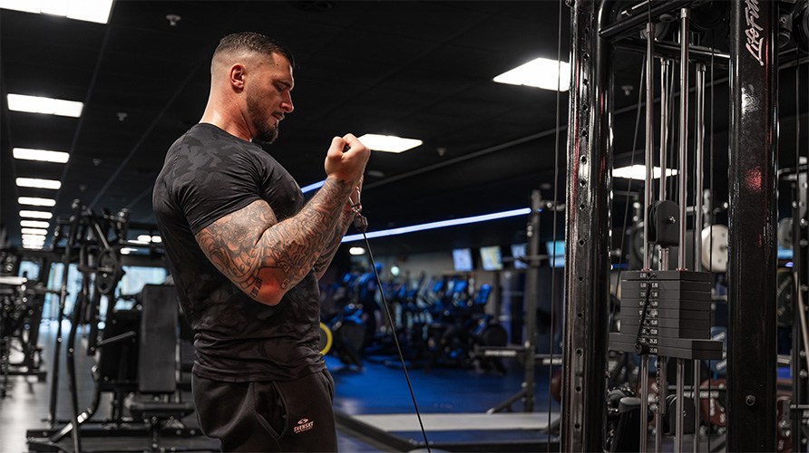En mand udf�rer bicepscurl i kabelmaskine i fitnesscenteret.