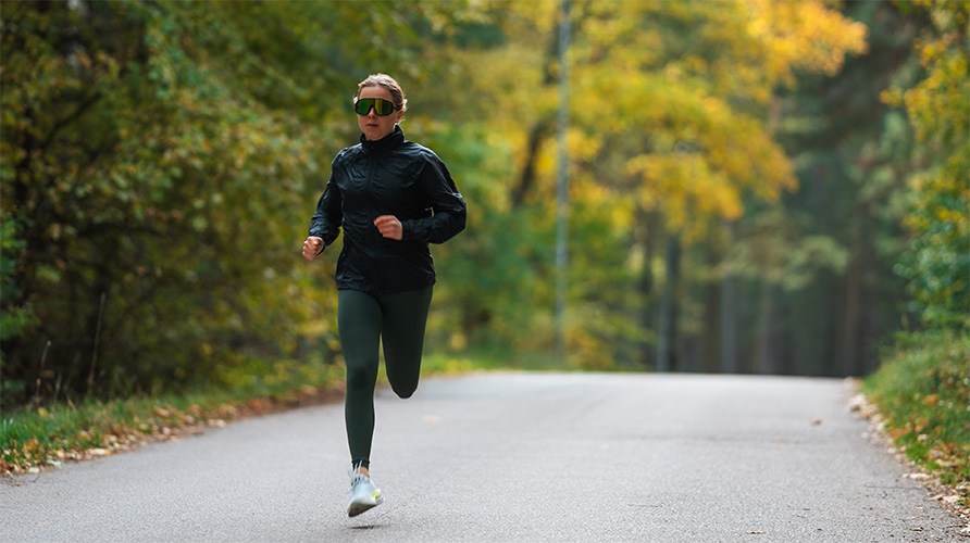 En kvinde lber p en vej i en skov.