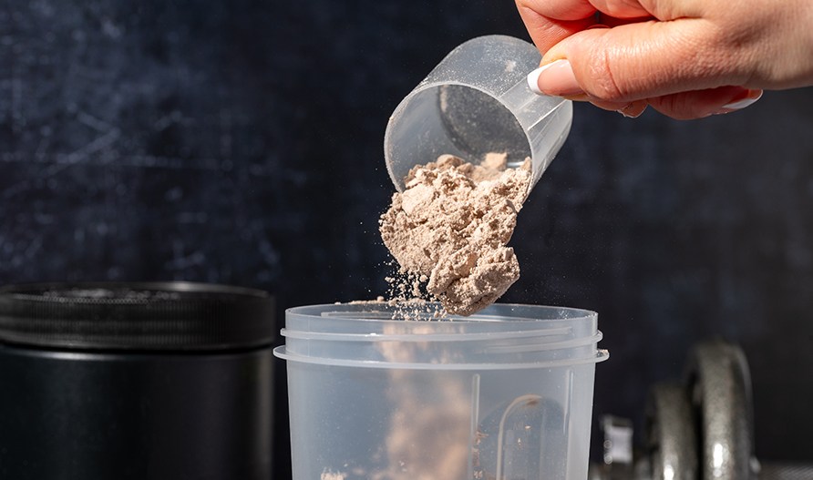 En hnd hlder kasein pulver i en shaker.
