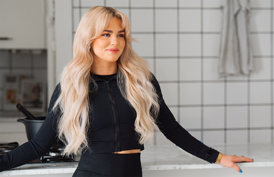 En smilende kvinde lner sig op af et kkkenbord.