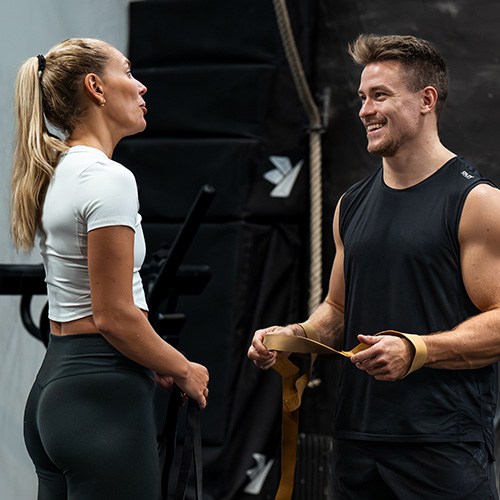 En tjej och en kille i trningsklder pratar med varandra. 